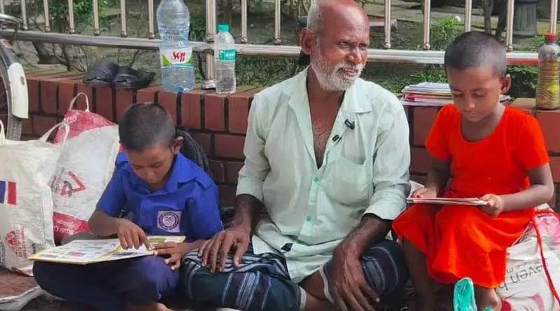 খোলা আকাশের নিচে জুতা সেলাই করছেন বাবা, পাশে বই পড়ছে ছেলে-মেয়ে